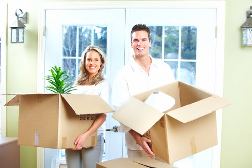 Professional movers carrying household items through a Leyton property